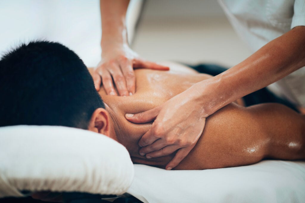 Un hombre tumbado recibiendo un masaje en la espalda